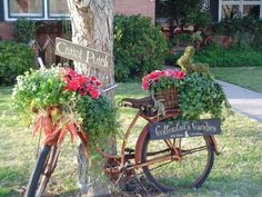 an old bicycle is decorated with flowers in front of a house