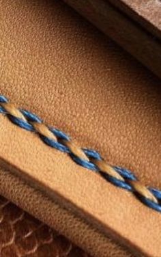 a blue and white braid on the inside of a brown leather case with an open zipper