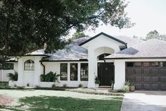 a white house with brown garage doors and windows