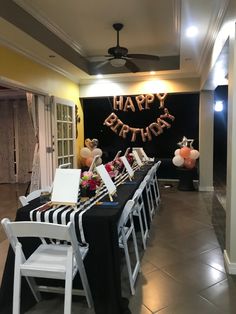 a birthday party with black and white table cloths, balloons and decorations on the wall