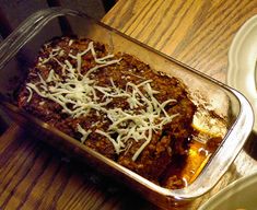 a casserole dish with meat and cheese in it sitting on a wooden table