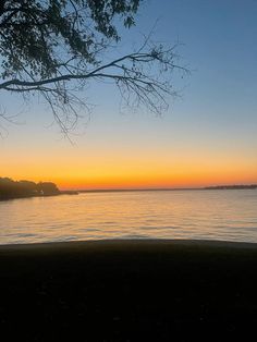 the sun is setting over the water and trees