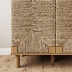 a large woven storage basket sitting on top of a wooden floor next to a white wall