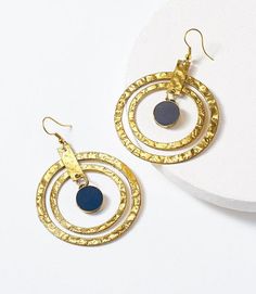 Update your hoop earring game! These handcrafted drop earrings feature a smooth brass cobalt-colored charm in a hammered, gold finish cascade hoop setting. They are a fun way to easily dress up an outfit! Blue Hammered Drop Earrings, Blue Brass Hoop Jewelry, Blue Hoop Brass Jewelry, Blue Brass Hoop Earrings, Old Delhi, Ornate Jewelry, Floral Cocktails, Brass Hoop Earrings, Hammered Hoop Earrings