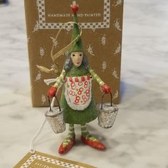 a ceramic figurine holding two buckets on a table next to a greeting card