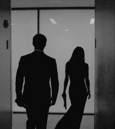 a man and woman standing in front of a glass door with the reflection of them