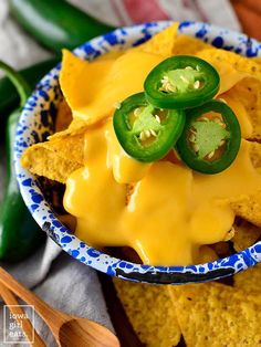 a blue and white bowl filled with nachos topped with jalapenos