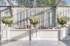 three white tables with vases and flowers on them