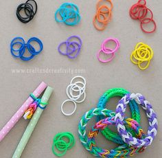 several different colored bracelets and a pen on a table next to some rubber bands