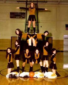 a group of cheerleaders standing on top of each other in front of a basketball court