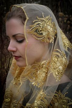 a woman wearing a veil with gold embroidery on it