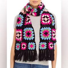 a woman wearing a black and pink crochet scarf with fringes on it