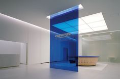 an empty room with white walls and blue glass partitions on the floor, in front of a wall that reads columbus