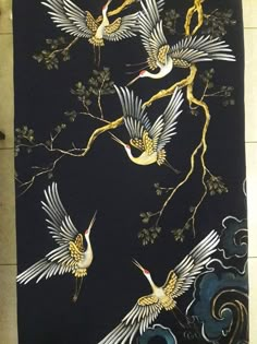 three birds are flying in the air on a black and gold wallpaper with swirls