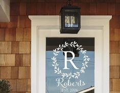 the front door is decorated with a wreath and monogrammed initials, along with a lantern light