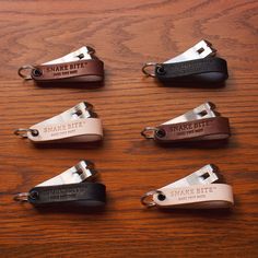 six leather key fobs on a wooden table