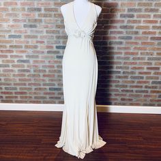 a white dress on a mannequin dummy next to a brick wall and wooden floor