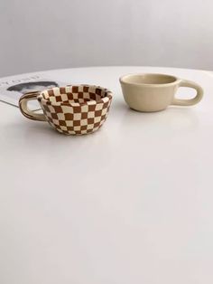 two cups sitting on top of a white table