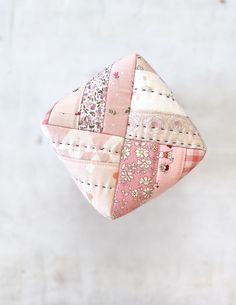 a pink patchwork pillow hanging on a white wall