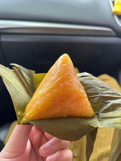 a person holding up a piece of food in their left hand while sitting in a car