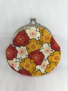 an orange and yellow flowered purse on a white background with silver clasp closures