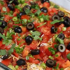 a casserole dish filled with black olives, tomatoes, cheese and cilantro