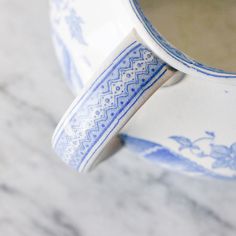 a blue and white cup sitting on top of a marble counter next to a mirror