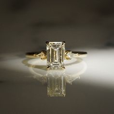 an engagement ring with a fancy emerald cut diamond in the center and three side stones on each side