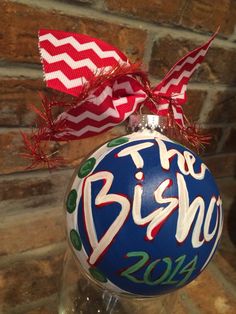 a christmas ornament hanging from a wine glass in front of a brick wall