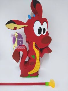 a paper cut out of a red dragon with horns and tail, holding a broom