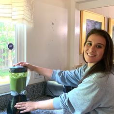 a woman is holding the lid on a blender in her hand and smiling at the camera