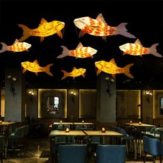 a restaurant with many fish hanging from the ceiling and tables in front of them, all lit up at night