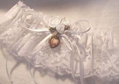 a white garter with two roses and a heart on the front, attached to a ribbon