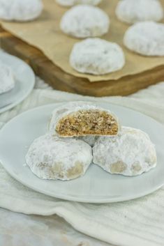 powdered donuts on a white plate with a wooden cutting board in the background