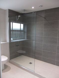 a bathroom with a glass shower door next to a toilet