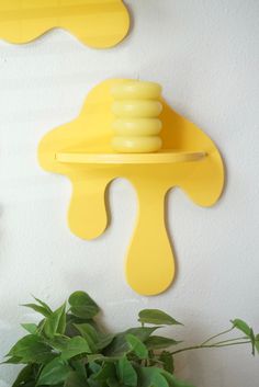 a potted plant sitting next to two yellow wall sconces on a white wall