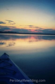 the sun is setting over water with a boat in it's foreground and clouds reflected in the water