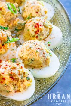 deviled eggs on a glass plate with seasoning