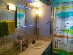 a bathroom with a sink, mirror and shower curtain in the corner that has an abstract design on it