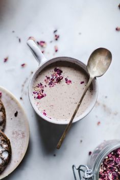 a cup of coffee and some cookies on a white table with pink sprinkles