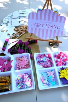 there are many crafting items in the trays on the table and one has a sign that says fairy wands