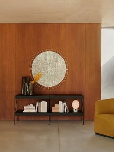 a living room with a couch, book shelf and round mirror on the wall above it