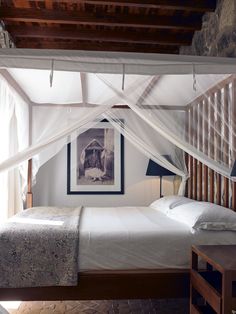 a white bed sitting under a canopy in a bedroom