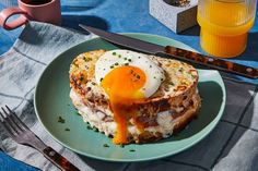 an egg is being drizzled over some food on a blue plate with utensils