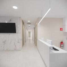 a long hallway with white marble walls and flooring on both sides is lit by recessed lights