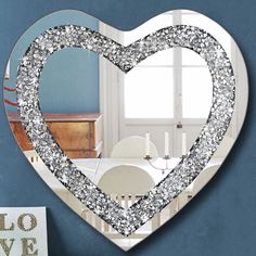 a heart shaped mirror hanging on the side of a blue wall next to a white chair