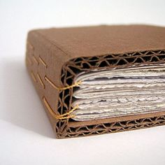 an open brown book with pages cut out and string wrapped around the edges, sitting on a white surface