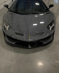 a grey sports car parked in a garage with its hood up and front lights on