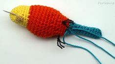 a crocheted orange and yellow object with pins in the middle on a white surface