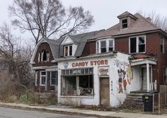 an old run down candy store on the corner of a street in front of a house